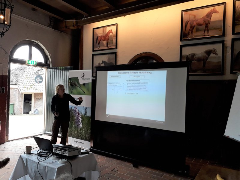 Collega Ariët Kieskamp staat bij een scherm met een powerpoint-presentatie.