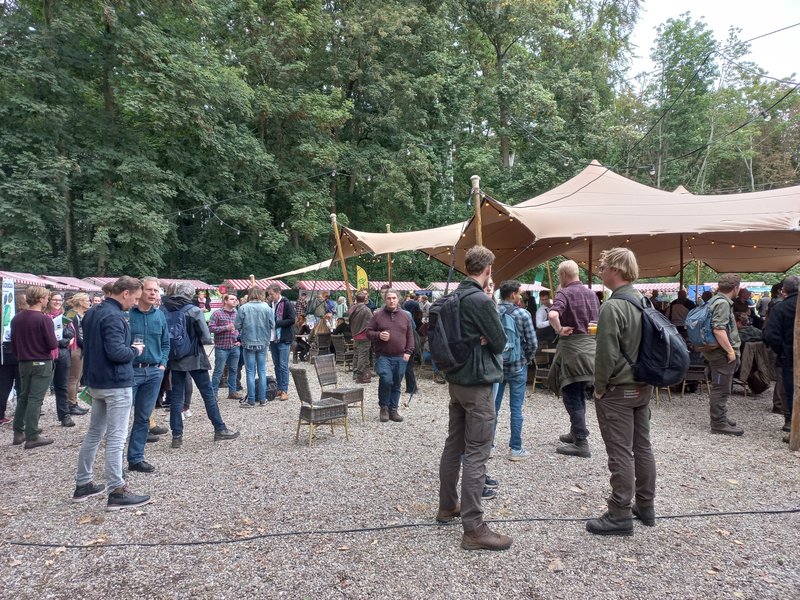 Veel mensen op de informatiemarkt van de Beheerdersdag. Zij praten of nemen een kijkje bij de informatiekramen.