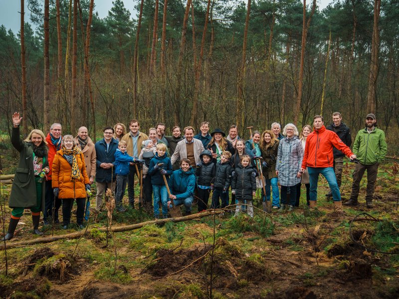 Groep mensen poseert in naaldbos.
